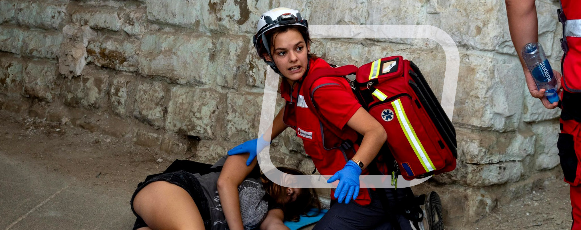 Lady paramedic with an Elite Bag Robust bag attending to a patient who is lying on the ground from the About Us page.
